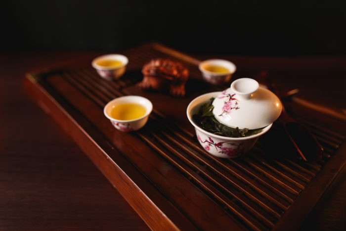 The Traditional Chinese tea ceremony. Porcelain gaiwan and three cups on a tea desk chaban.